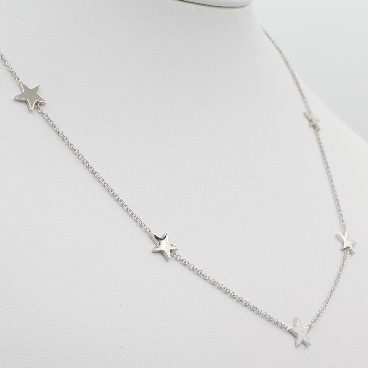 14k White Gold Five Station Star Necklace, close-up left angle view of necklace displayed on mannequin neckline.