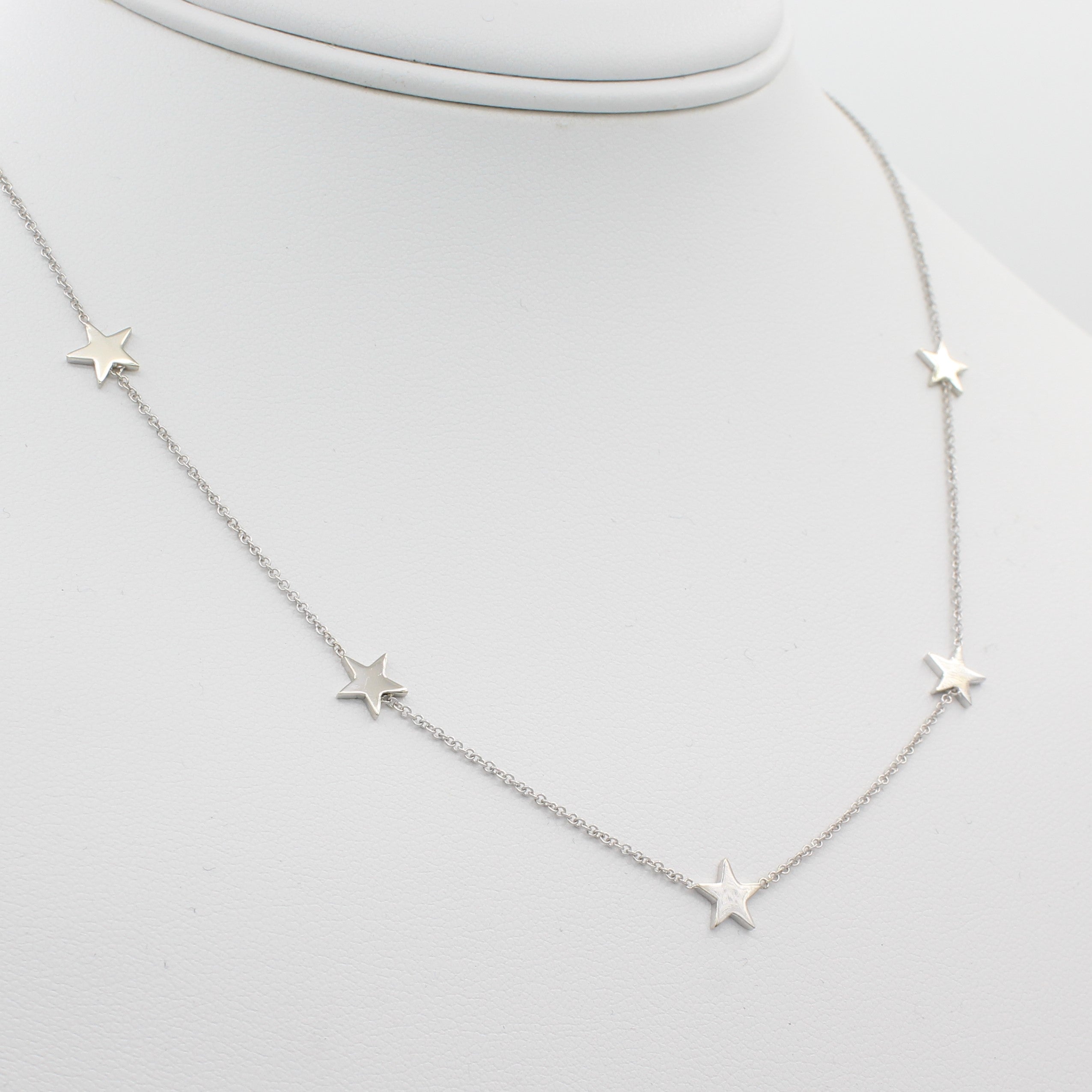 14k White Gold Five Station Star Necklace, left angle view of necklace displayed on mannequin neckline.