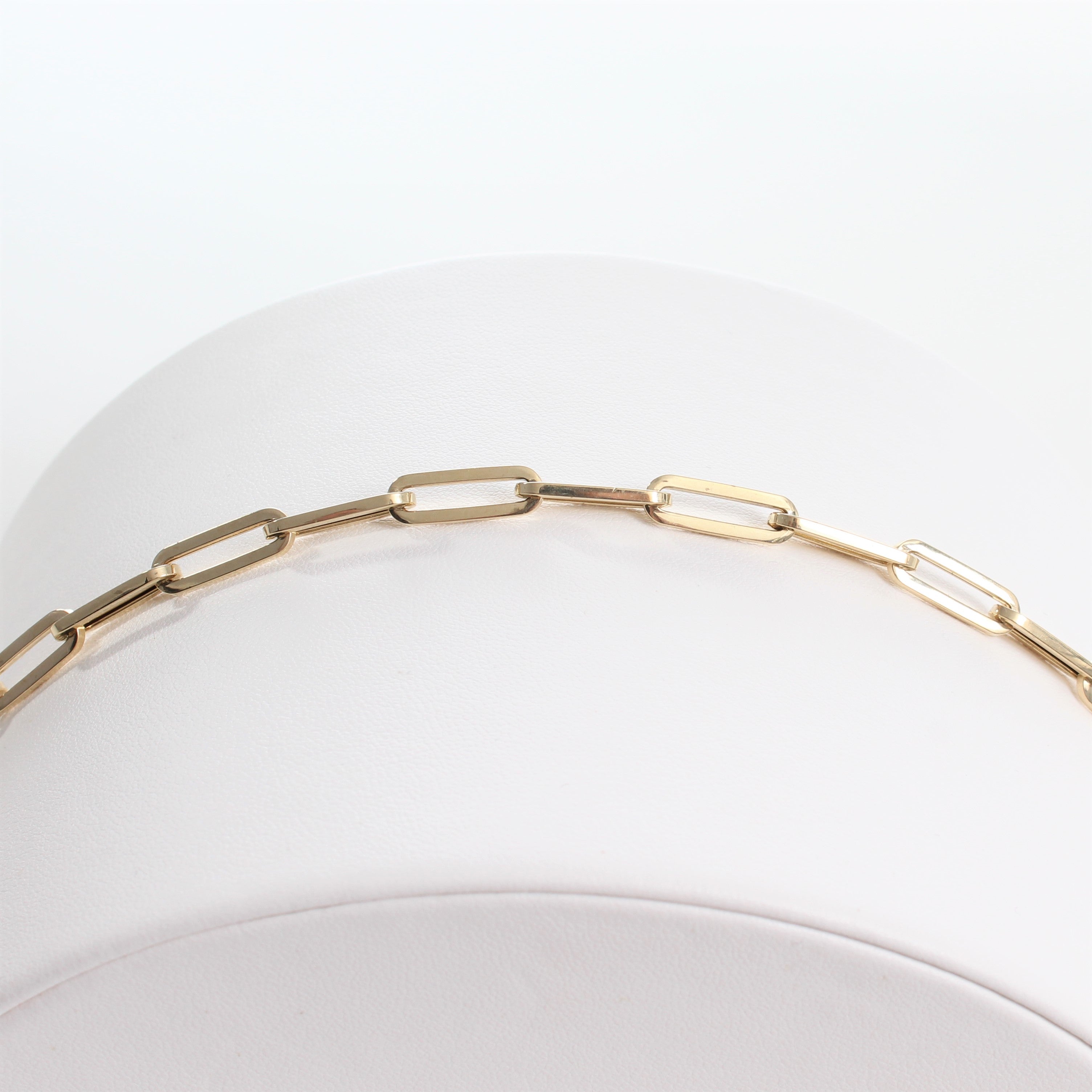 14k Yellow Gold Retro Elongated Link Paperclip Large Link Bracelet. close-up view of unclasped bracelet laid out on a white jewelry display.