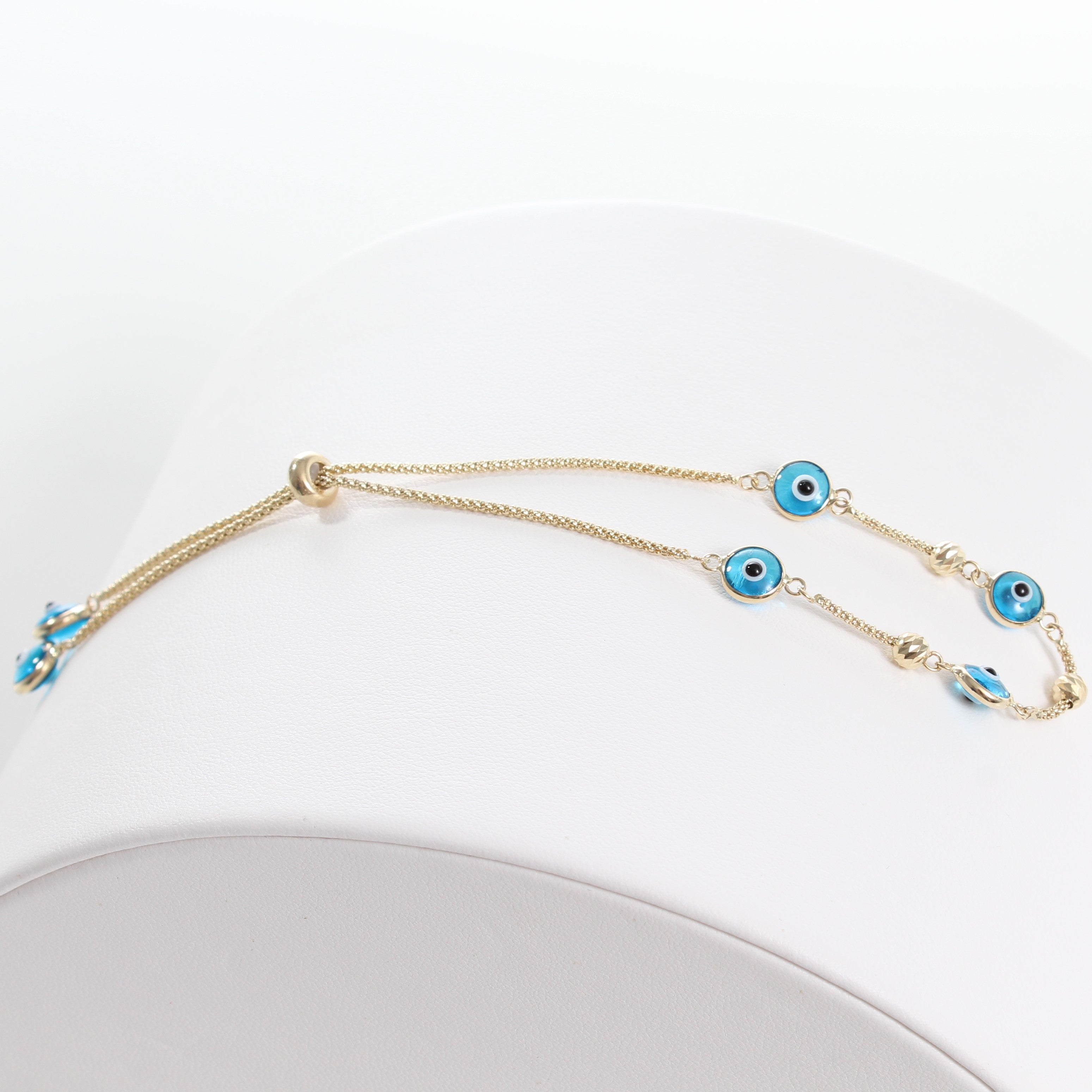 14k Yellow Gold Light Blue Evil Eye Beaded Bolo Bracelet, front view of clasped bracelet laid out on a white jewelry display. 