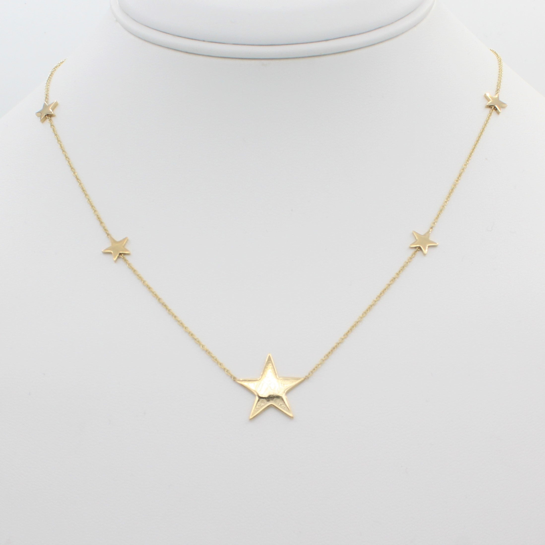 14k Yellow Gold North Star Five Station Necklace, close-up front view of necklace displaced on a mannequin neckline. 