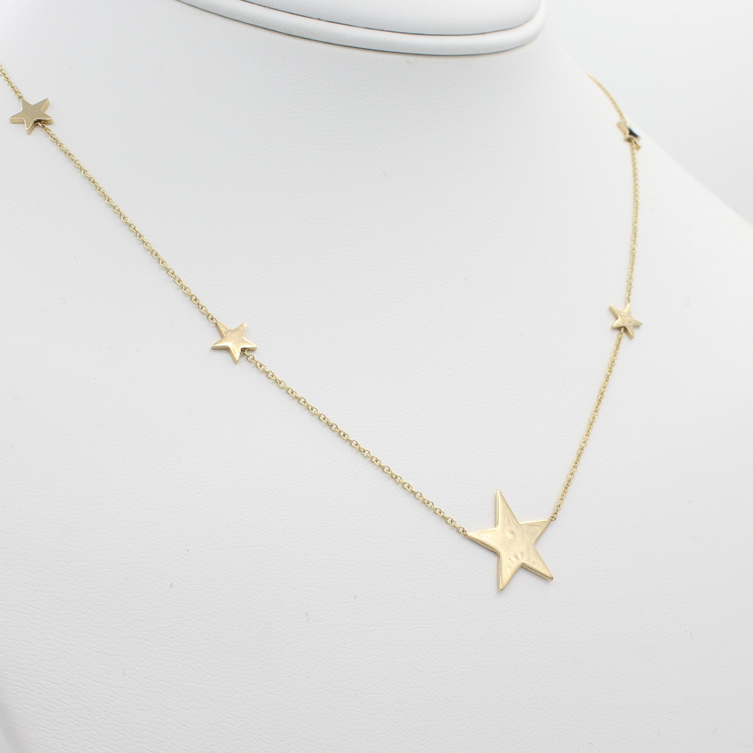 14k Yellow Gold North Star Five Station Necklace, close-up front view of necklace displaced on a mannequin neckline. 