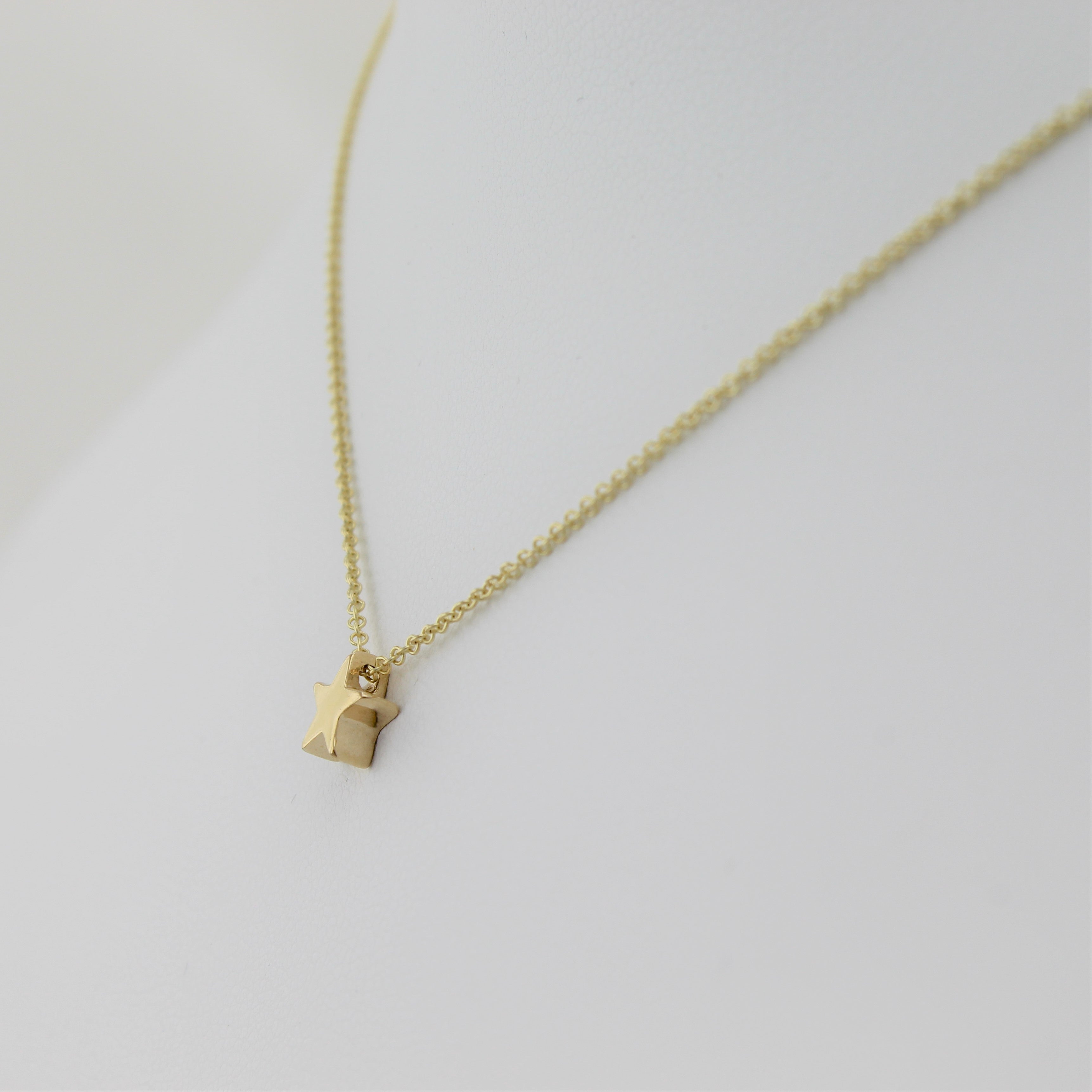 14k Yellow Gold Shining Star Pendant, close-up right angle view of the necklace displayed on a mannequin. 